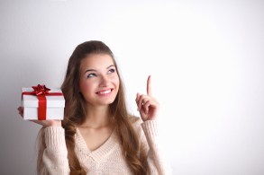 Young woman happy smile hold gift box in hands,standing over grey background