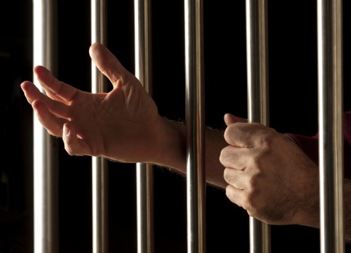 hands of a prisoner behind bars